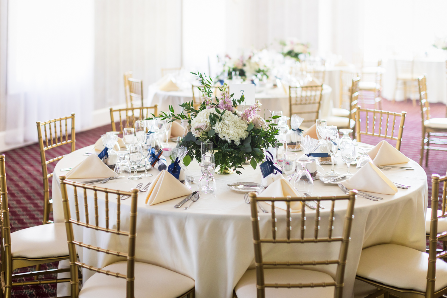 A table decorated for a wedding with white flowers and white tableware.